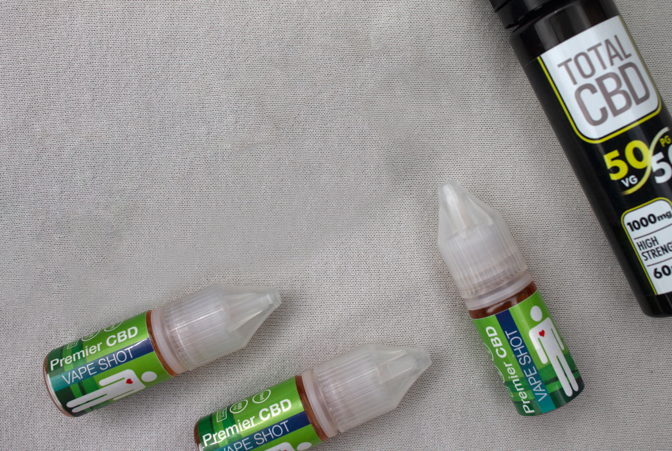 A number of CBD vape liquids laid out against a grey background